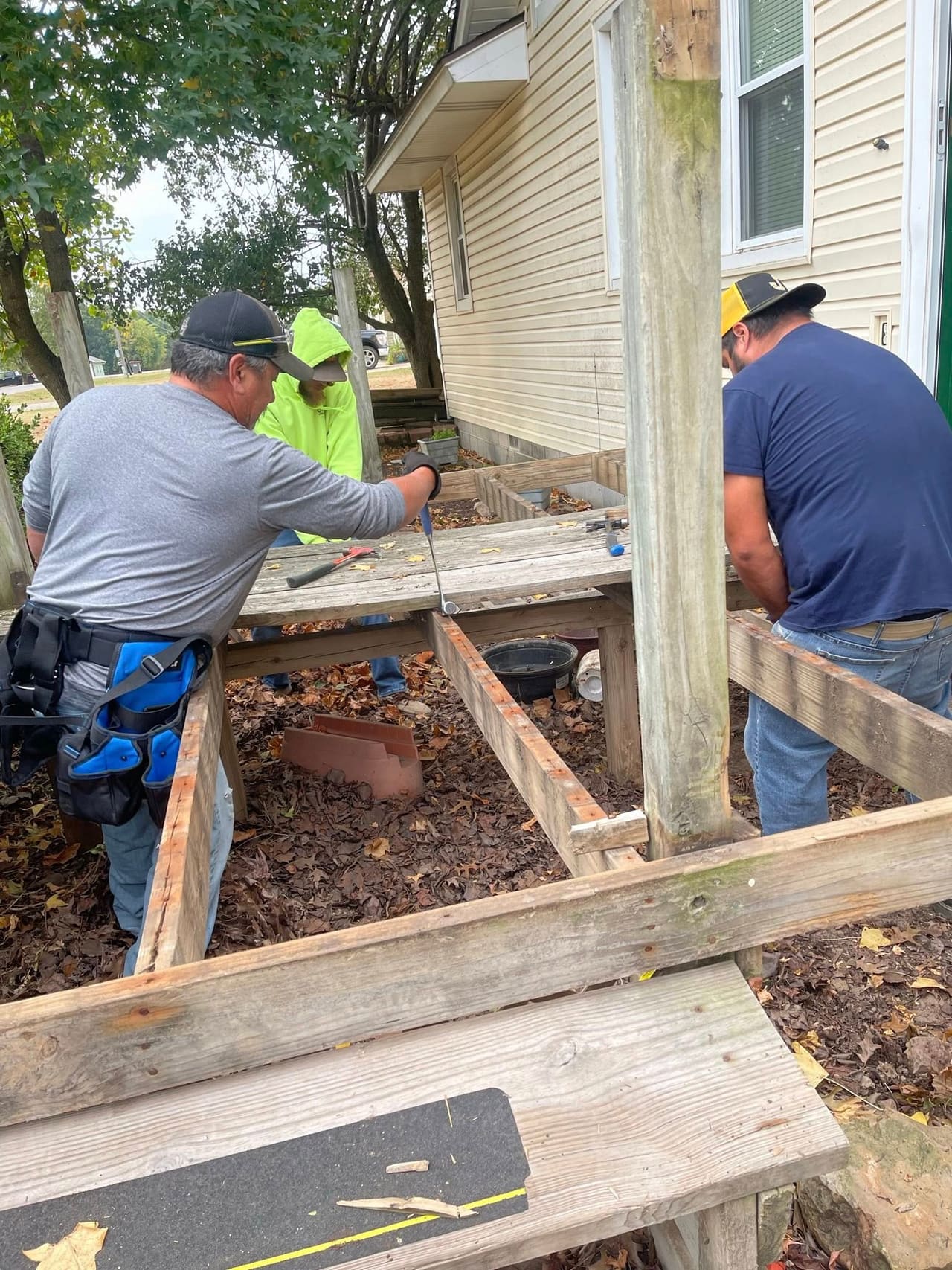 3D Fence & Construction crew building a wood deck frame against a home on a fall day