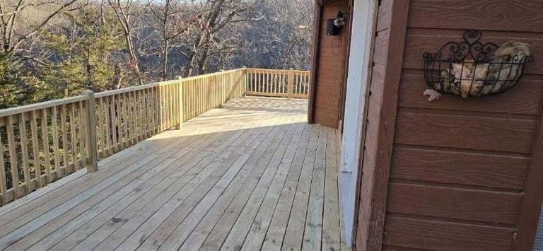 Newly built elevated cedar deck with wood handrail overlooking a wooded hillside